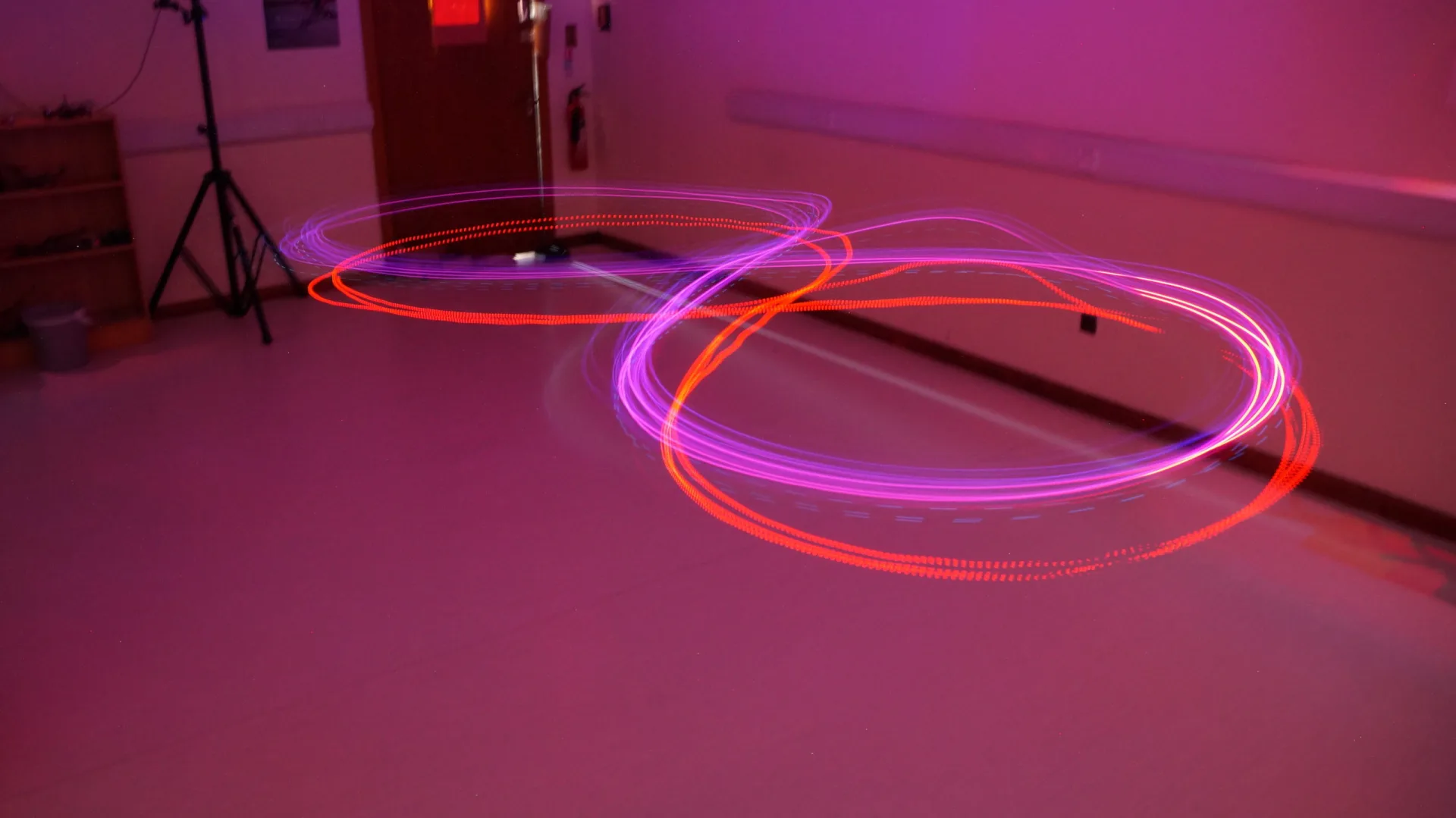 Long-exposure light painting of a drone's LED flight path traced against the dark