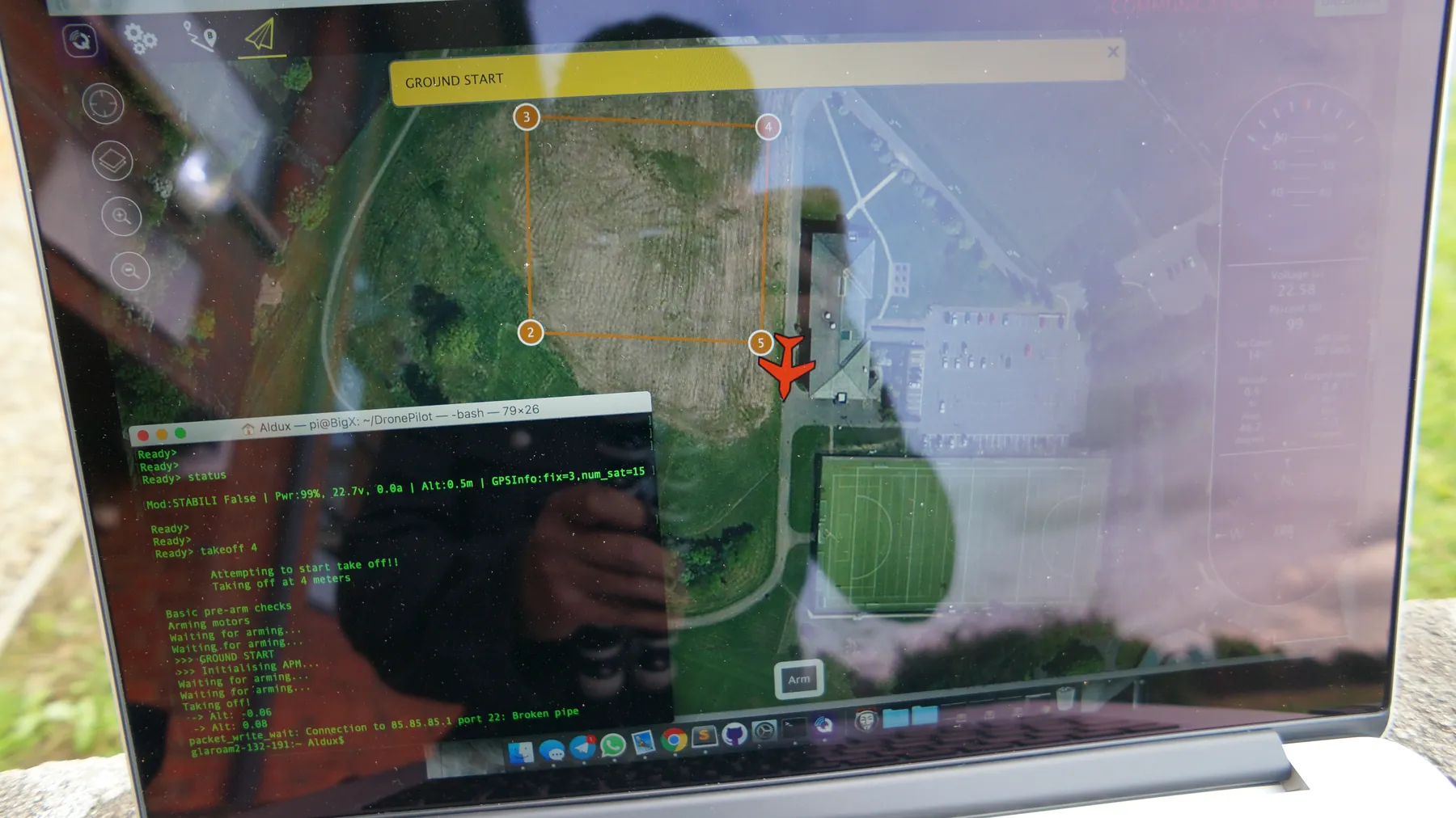 Laptop showing a terminal beside a satellite mission-planning map in the custom DronePilot software